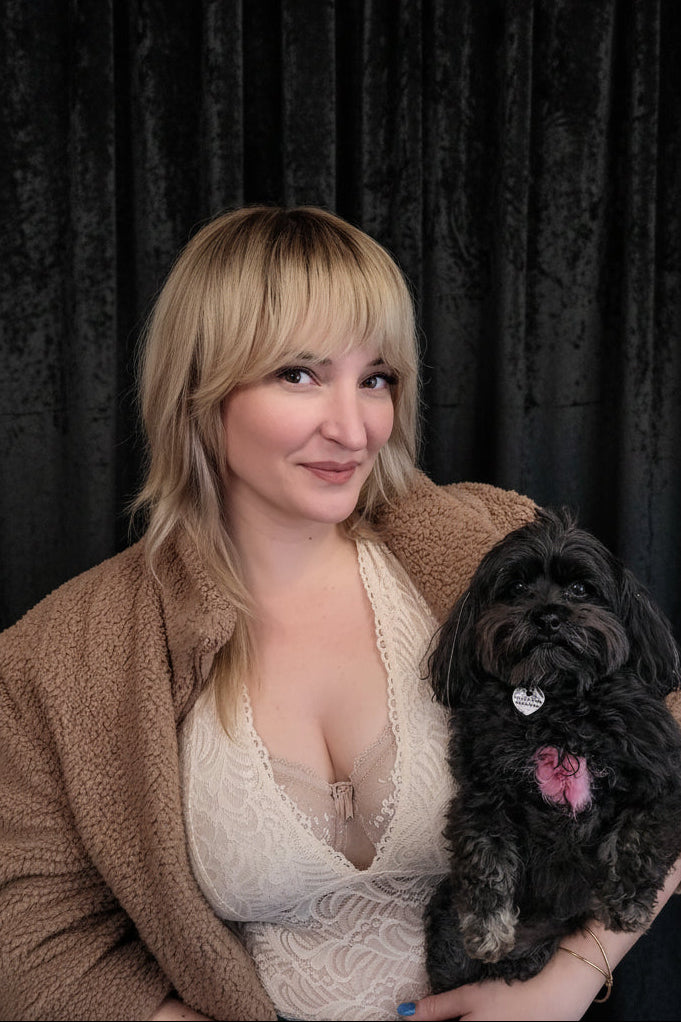 Woman holding a black dog in front of a decorative wall with chevron patterns.
