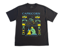 A black short-sleeve t-shirt with a colorful graphic print on the front featuring the word 'CAPRICORN' in light blue, along with various zodiac-themed illustrations and text in yellow, green, and white.