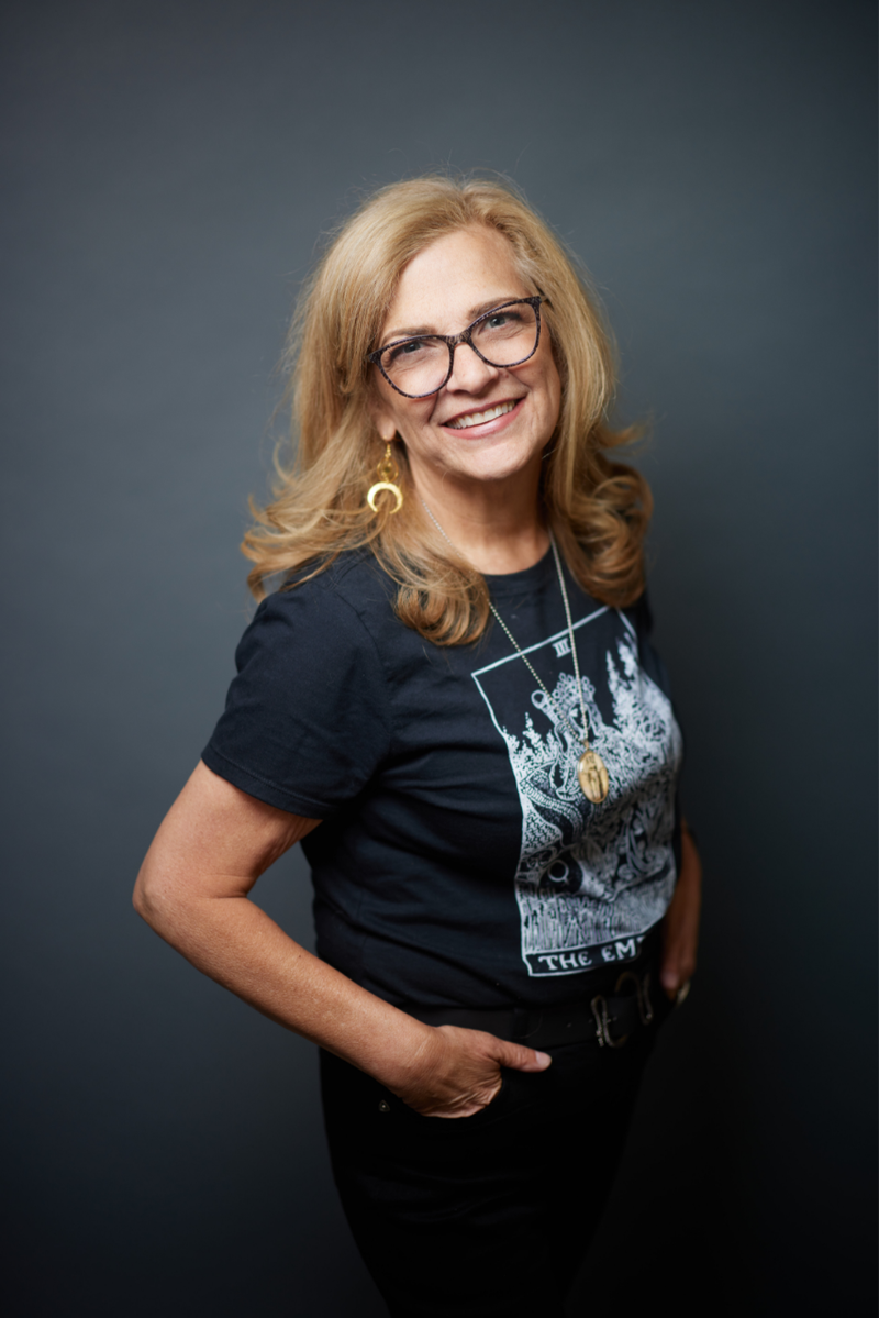 Woman wearing a black t-shirt with graphic design against a dark background