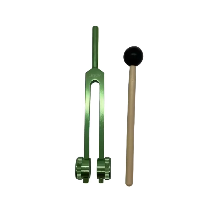Green tuning fork and wooden mallet on a gray background