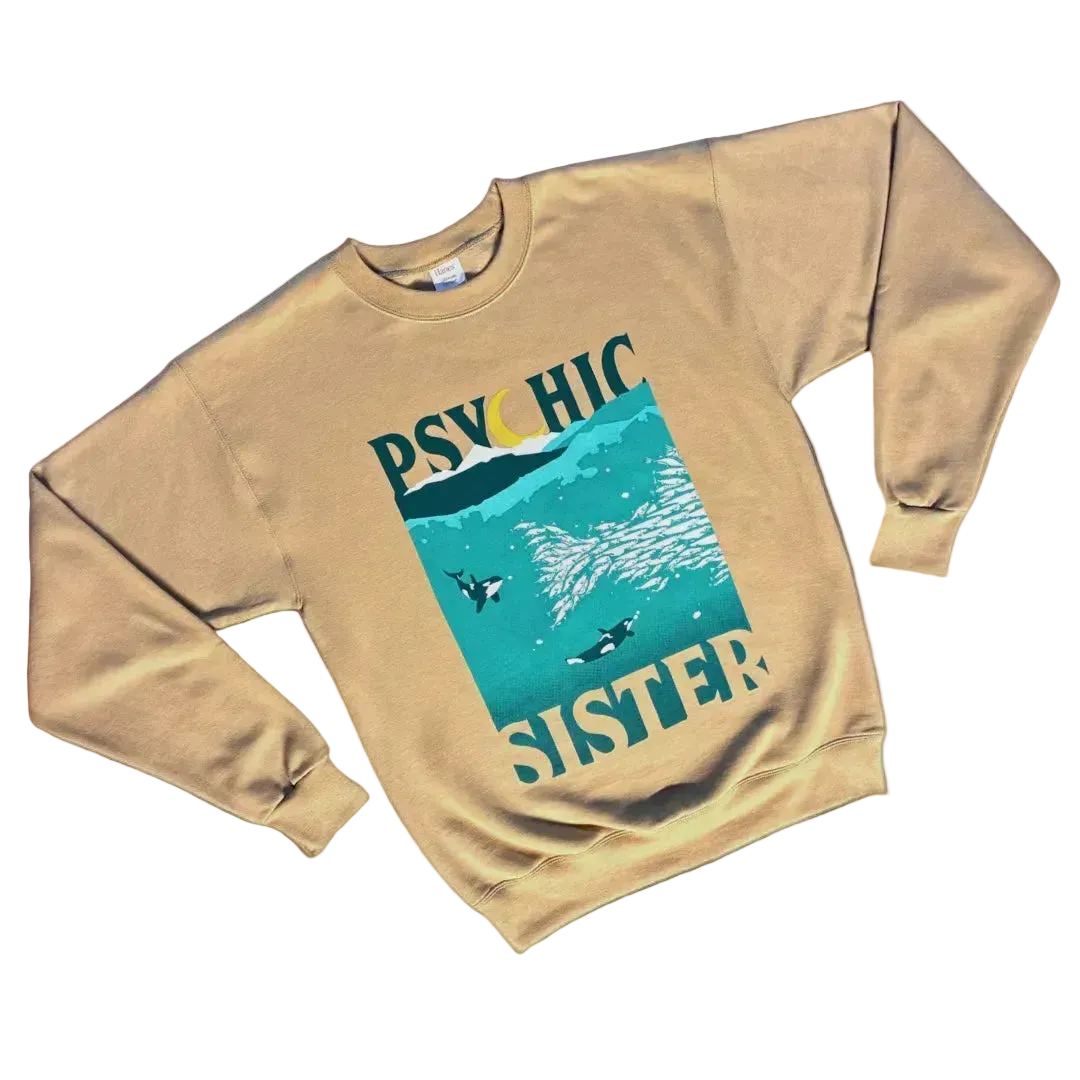Beige sweatshirt with graphic design and text on a white background image features orcas chasing school of fish with Psychic Sister in big letters on top and bottom
