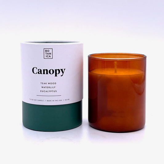 Amber Glass Candle next to White & Green Tube Package with Black Text