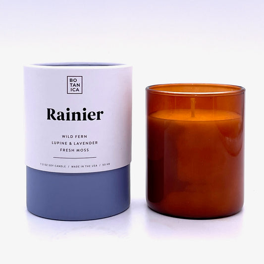 Amber Glass Candle next to White & Blue Tube Package with Black Text