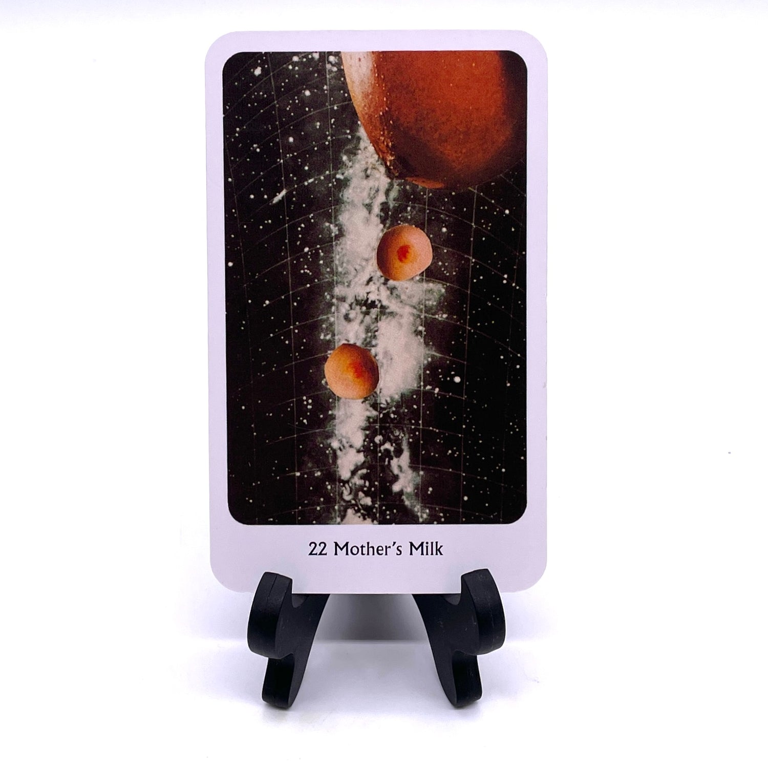 Photo of Card #22 "Mother's Milk", featuring collaged images of breasts against a grided Milky Way background.