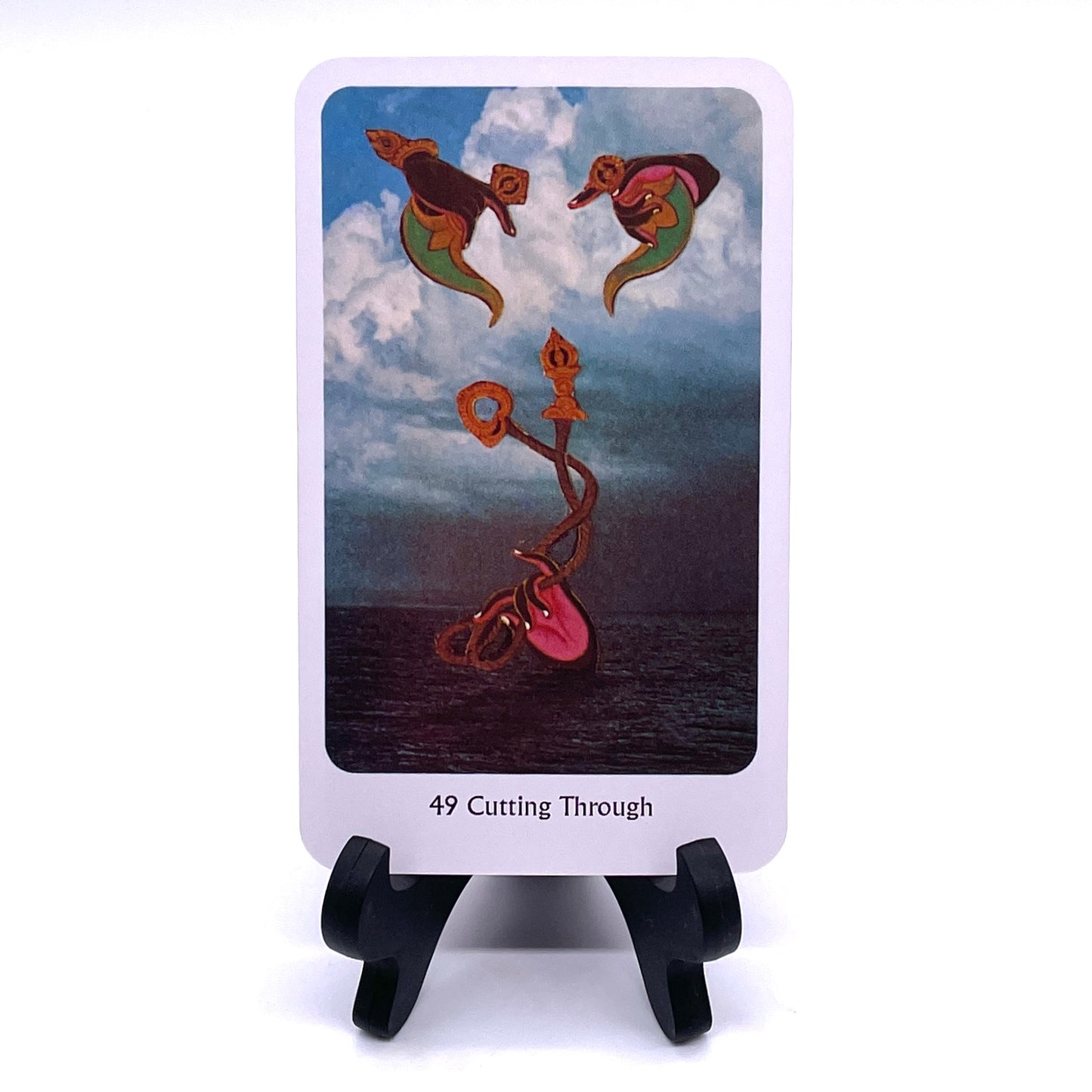 Photo of Card #49, "Cutting Through", featuring collaged images of oil lamps over a hand holding twisted scepters against an oceanscape background.