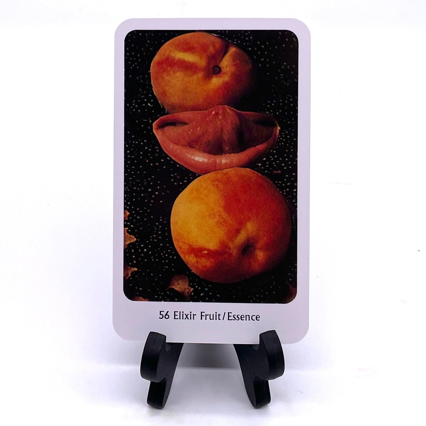 Photo of Card #56 "Elixir Fruit/Essence" featuring collaged images of stone fruit and a mouth with the tongue sticking out, against a starry backdrop.