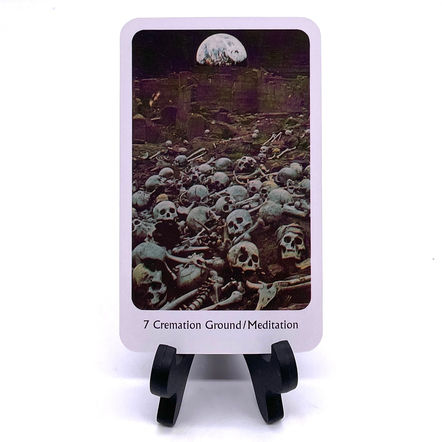 Photo of card #7 "Cremation Ground/Meditation" featuring collaged images of a boneyard scene with cliffs and the moon in the background.