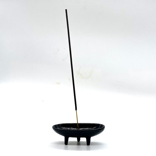 Cast iron incense burner with incense stick.
