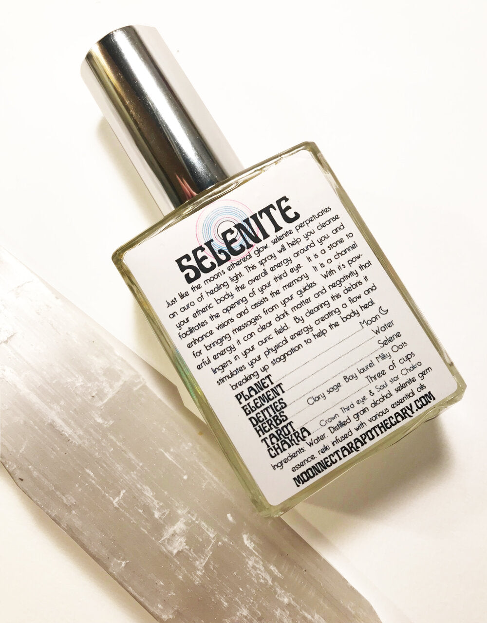 Selenite spray bottle next to a selenite wand crystal.