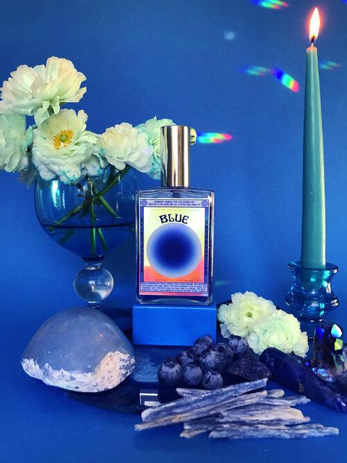 Moon Nectar Vibrational color spray in blue displayed with flowers and crystals.