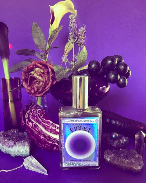 Moon Nectar Vibrational color spray in violet displayed with flowers and crystals.